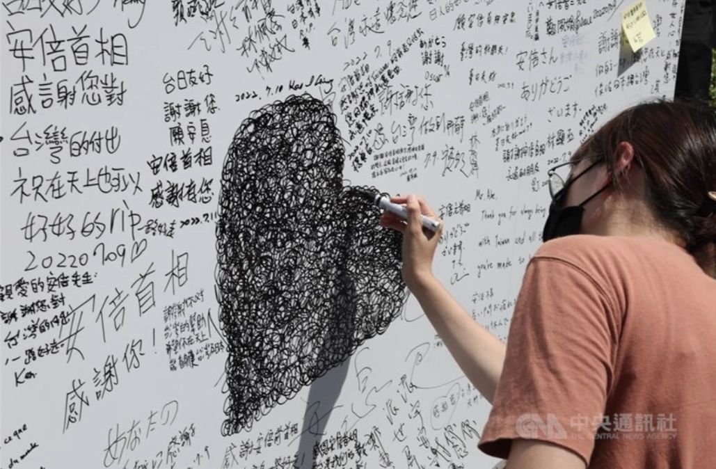 ▲ 日台交流協會前悼念安倍晉三的留言牆被人惡搞，一位女孩用愛心塗鴉巧妙蓋住謾罵字眼，以愛戰勝仇恨的創意讓網友大讚。中央社記者趙世勳攝　111年7月10日