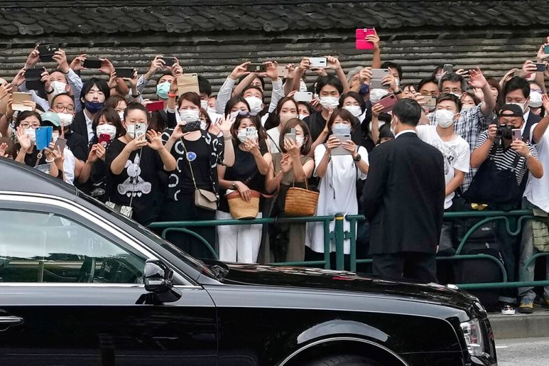 ▲日本前首相安倍晉三喪禮,民眾在外等候向沿途經過的靈車揮手告別。(圖/美聯社/達志影像)
