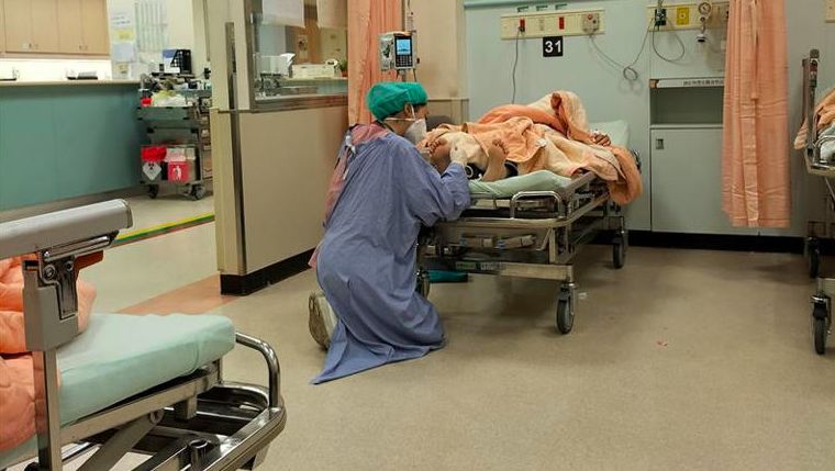▲一名急診護理師，雙膝跪下在病患腳邊為他抽血。（圖／翻攝自爆廢公社）