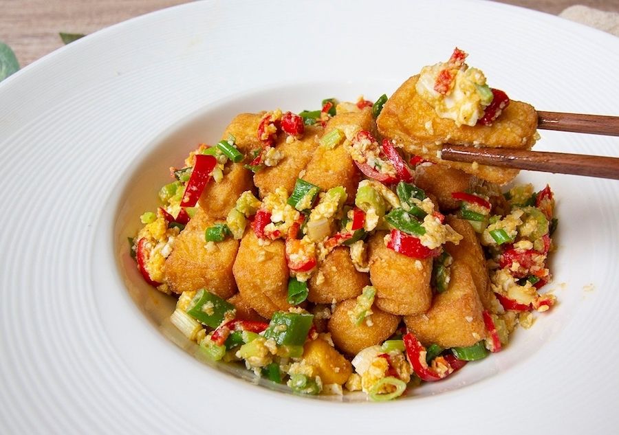 ▲大塊雞蛋豆腐酥炸至金黃色，並將鹹蛋黃壓碎與蒜頭、蔥花等調味食材一同在鍋內拌炒，中和了酥炸的油膩。（圖／NOWnews資料照片）