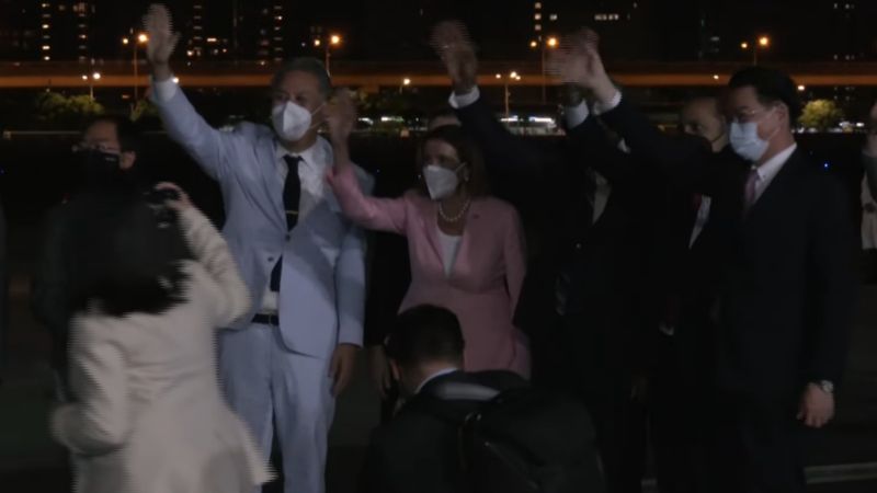 ▲裴洛西（中間粉色西裝）抵達台灣，和外面等候的群眾、媒體們揮手致意。（圖／外交部）