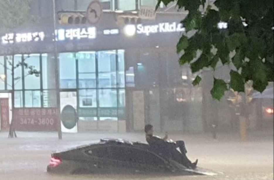 ▲男子因道路淹水，無奈受困於車頂。（圖／翻攝自推特）