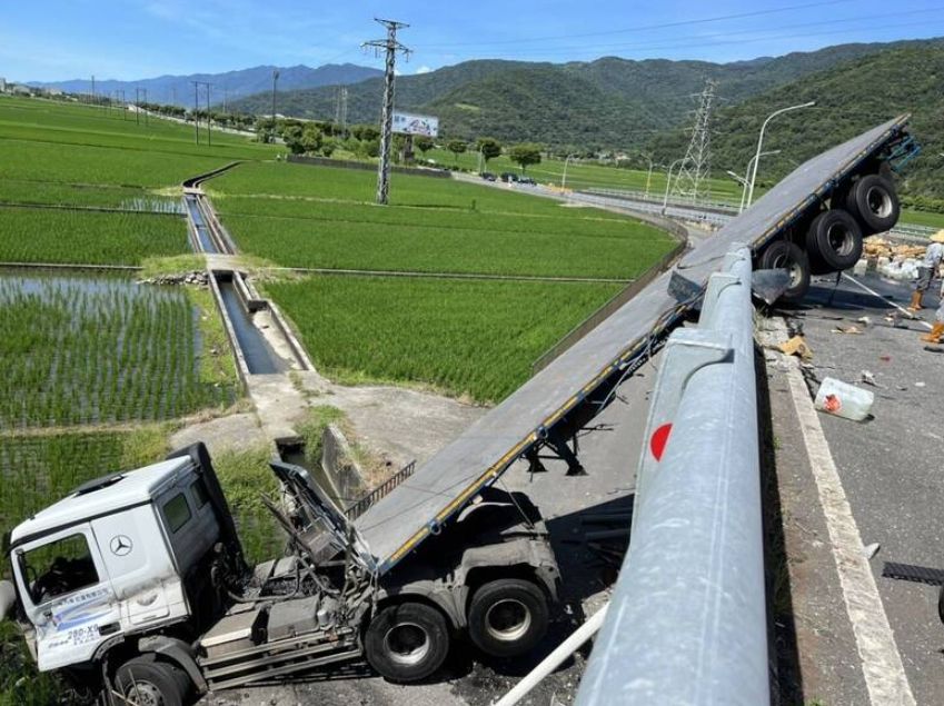 ▲現場一輛拖板車行經一處彎道時，不明原因失控，整輛車衝出護欄，車頭墜落10多公尺高的富里大橋，但是車身仍卡在橋上。（圖／翻攝畫面）