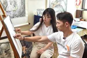 ▲温昇豪（右）向弱勢女孩學用炭筆畫蘋果。（圖／台灣世界展望會）