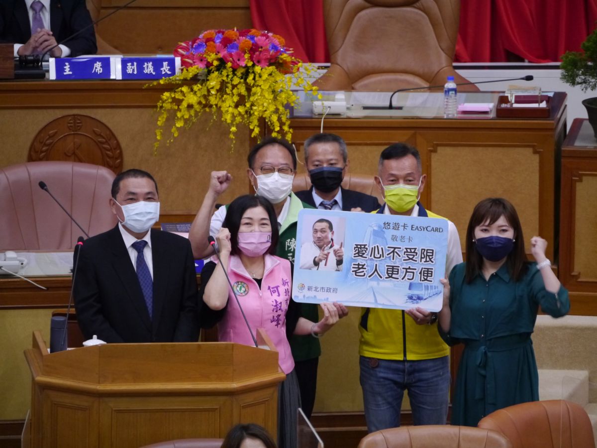 ▲新北市議會民進黨團張維倩、何淑峰、李余典及陳永福共同送上一張印有侯友宜照片的敬老卡看板給備詢的侯友宜。（圖 ／記者吳嘉億攝，2022.9.13）