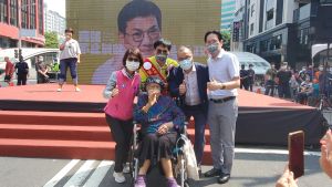 ▲吳益政90歲的媽媽，也坐在輪椅上，為吳益政披掛彩帶。(圖／翻攝畫面)