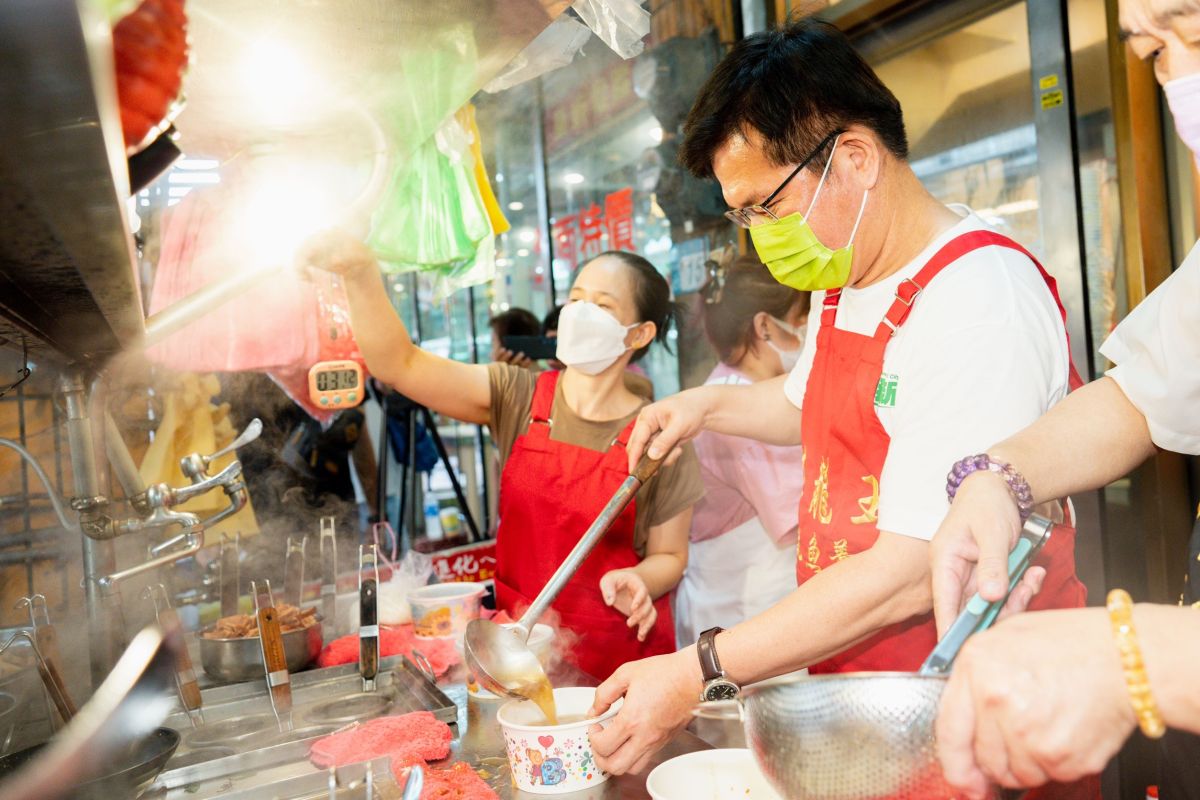 ▲林佳龍到汐止的排隊美食魷魚羹店，化身店長幫忙並進行義賣，幫助在地廟宇濟德宮作為重建基金。（圖／林佳龍競選辦公室提供）