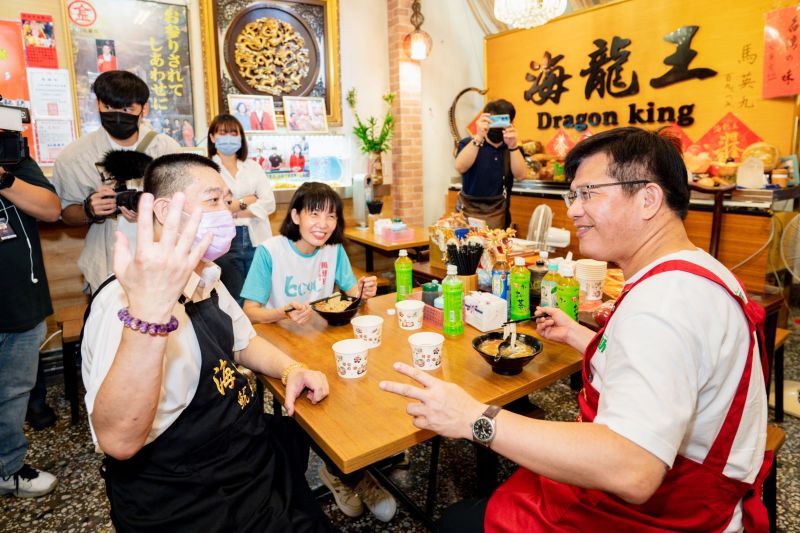 ▲林佳龍到汐止的排隊美食魷魚羹店，化身店長幫忙並進行義賣，與老闆及居間協助的市議員周雅玲閒話家常。（圖／林佳龍競選辦公室提供）