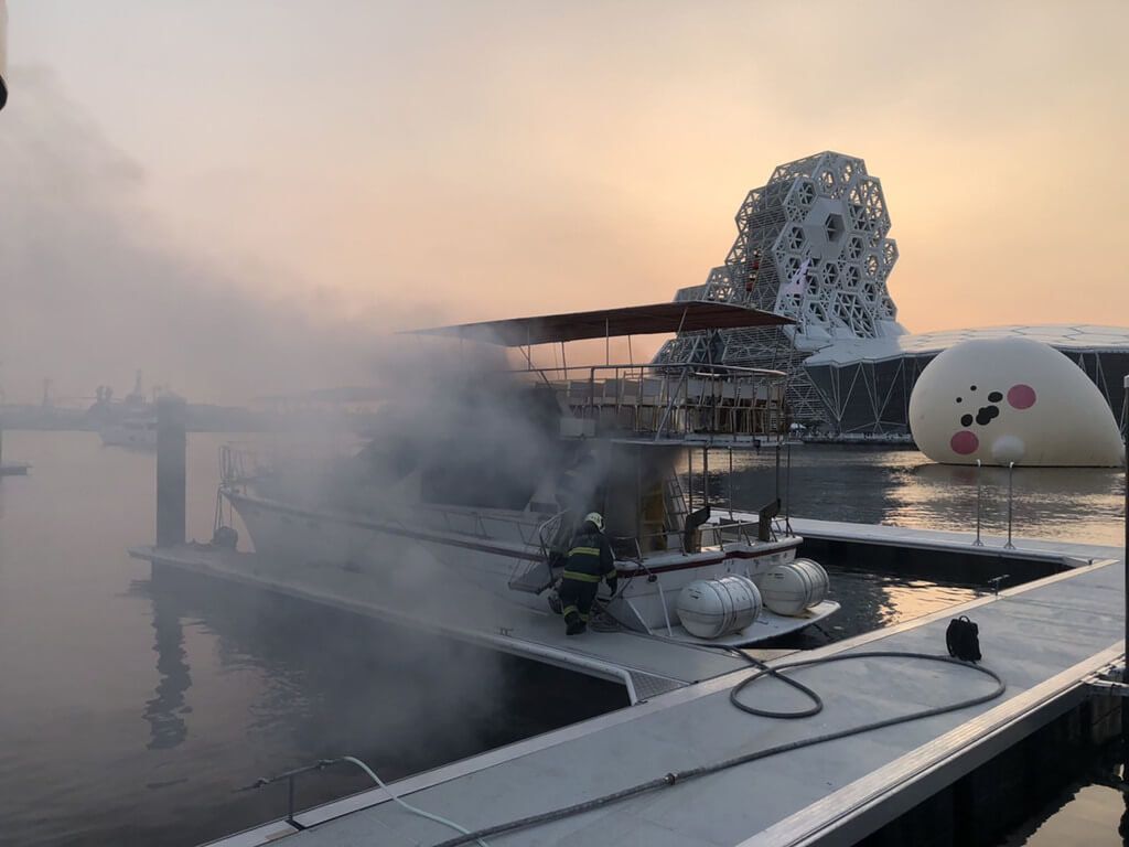 ▲高雄市苓雅區光榮碼頭一艘停靠岸邊遊艇1日突然起火燃燒，現場濃煙陣陣，消防人員獲報出動人車到場搶救，遊艇內部嚴重燒毀，所幸未釀人員傷亡。（高雄市消防局提供）中央社記者洪學廣傳真 111年10月1日