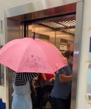 ▲台北南港Citylink停車塔的電梯漏水，民眾撐著傘跨過水簾搭乘。（圖／臉書社團《路上觀察學院》）