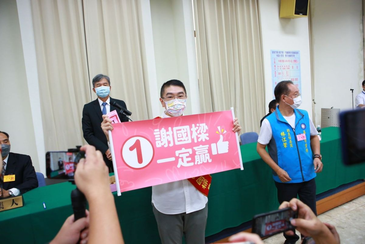 ▲謝國樑步行遊到基隆市選委會，抽到1號，手拿幸運號次的布條象徵一定贏。（圖 ／謝國競選辦公室提供）