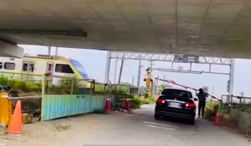 ▲一輛黑色自小客車「違停」在平交道上，火車見狀緊急煞停，沒想到轎車乘客不慌不忙，走上前將柵欄扶起，讓轎車倒退後，更揮手示意列車可以「通過」了，火車才緩慢前進。（圖／翻攝自臉書我是柳營人）