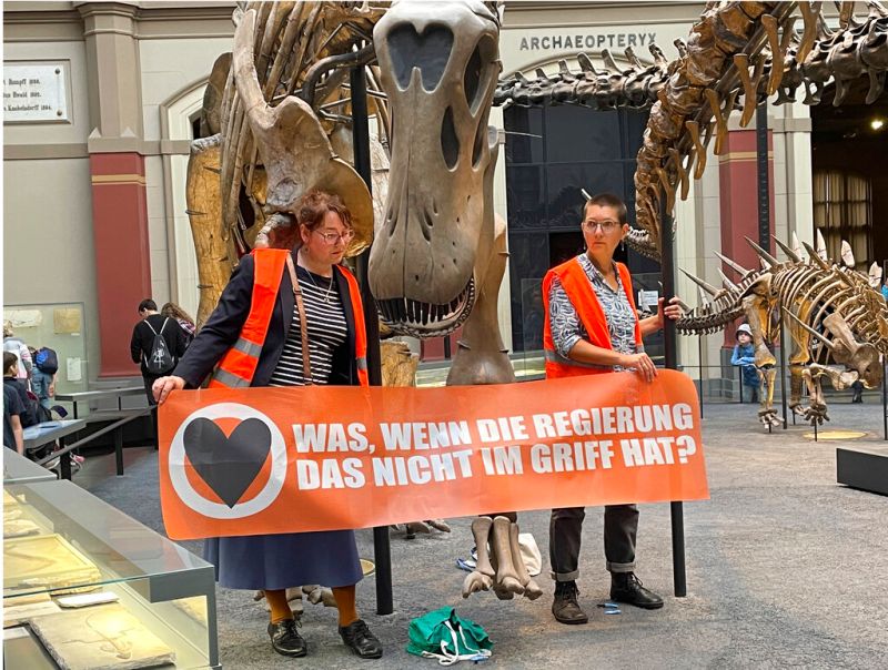 ▲德國兩名環保人士30日在柏林自然博物館將自己黏在恐龍骨架下方的支柱，抗議政府氣候政策。（圖／美聯社／達志影像）