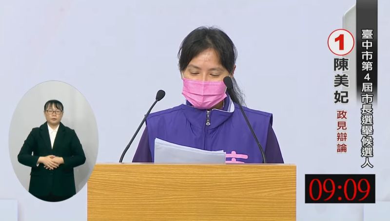 ▲陳美妃全程戴口罩,她說自己第一次上台有點緊張,隨即拿起小抄說明政見。(圖/翻攝自台中市選委會YouTube,2022.11.15)