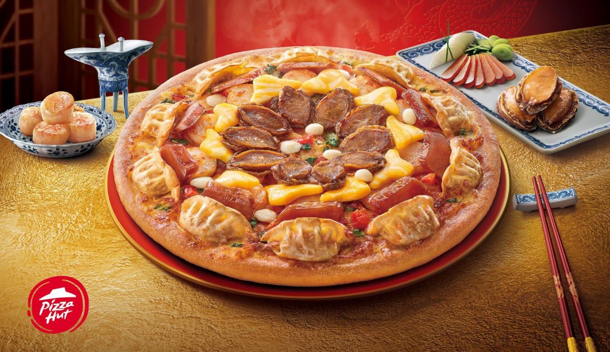 ▲必勝客迎接農曆新年，推出兩款開春限定超狂比薩力拚整桌年菜，「奢華加貝烏金鮑魚比薩」放滿10顆完整鮑魚＋烏魚子＋干貝；並加入「和風起司金元寶」，用水餃環繞比薩一整圈。（圖／必勝客提供）