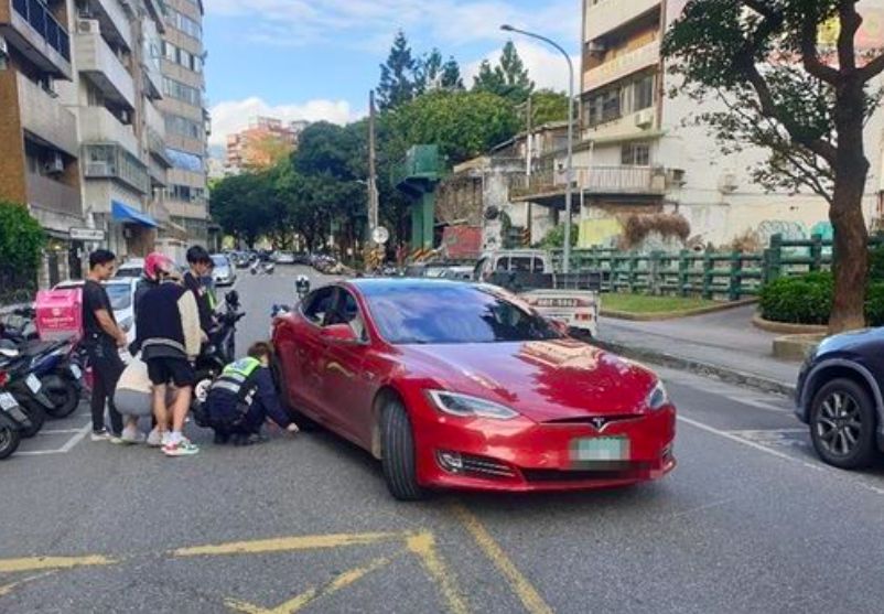 ▲一輛特斯拉和Gogoro電動機車發生碰撞而卡死，警方使用千斤頂解除排除現場狀況。（圖／翻攝畫面）