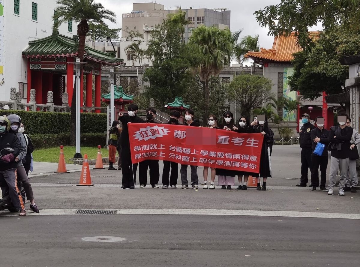 ▲112年度的學測結束，有考生在最後一天發現，建中考場門口有「重考生親友團」，還拉紅布條加油，笑翻不少人。（圖/路上觀察學院）