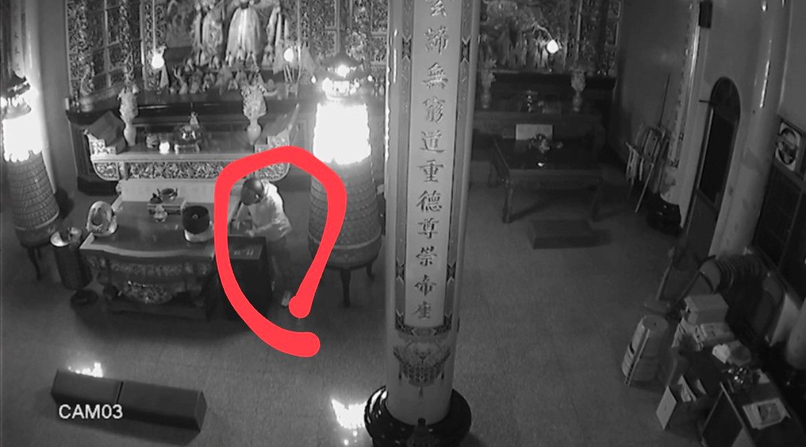 ▲竊嫌對著香油桶不斷地上下揮舞雙手，香油錢就被「釣」了上來。（圖／翻攝畫面）