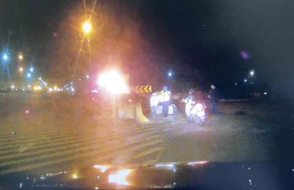 ▲64歲鄭姓男子昨天開車硬闖台中港管制站，自撞水泥護欄引發火燒車，警方將他救出送醫，鄭男趁醫護忙碌時自拔點滴離院，台中港務警察總隊請港務單位通知鄭男到案說明。（圖／民眾提供）
