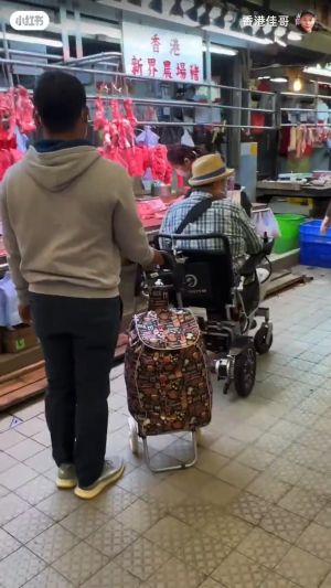 ▲洪金寶（右）坐輪椅逛市場買豬肉。（圖／翻攝自小紅書）