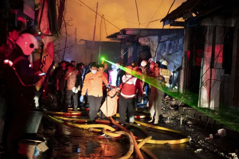 ▲印尼雅加達3日晚間發生油庫爆炸、引起大火的事故，釀成死傷。圖為消防人員抬著屍袋。（圖／翻攝自印尼羅盤報）