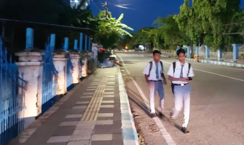 ▲天色未亮的街道上，睡眼惺忪的印尼古邦學生，正在前往學校的路上。（圖／翻攝自衛報）