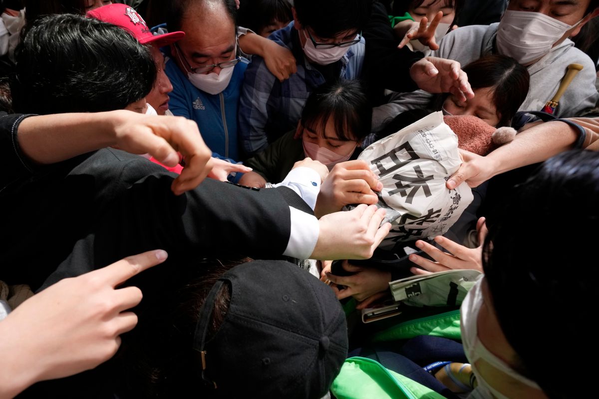 ▲棒球經典賽日本奪冠，日本民眾平日中午在爭搶「號外」，些許報紙都被搶到爛掉。（圖／美聯社／達志影像）