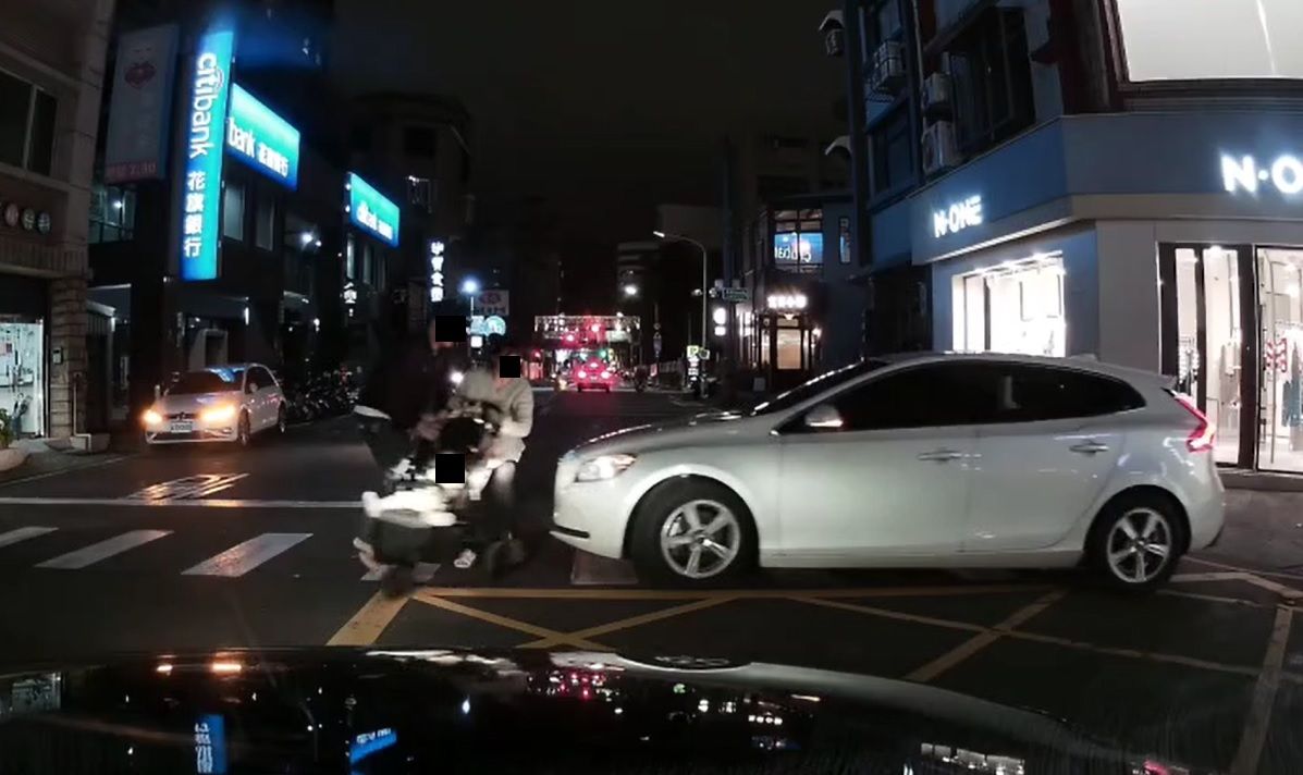 ▲白色汽車疑未注意有對夫妻推著嬰兒車過馬路，竟直直衝過去，嚇得夫妻行人急忙轉身，用肉體護著嬰兒車。（圖／翻攝爆料公社） 