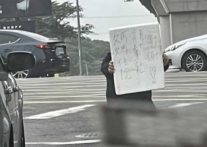 ▲一名男子在斑馬線中央下跪，並手舉著一塊牌子，寫著「媽媽住院請幫忙！謝謝」。（圖／翻攝林口大家庭LinKou-Family） 