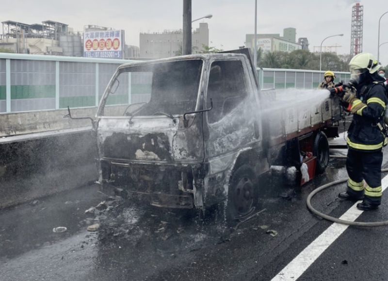 ▲國道1號北向356.3公里高雄楠梓段8日上午發生火燒車意外，一輛自小貨車行進間突然起火燃燒，緊急停到路肩，所幸車上2人順利逃生均無受傷；消防人員獲報前往撲滅火勢。（國道公路警察局提供）