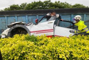 ▲小客車被擠壓到中央分隔島，駕駛驚險爬出，但下半身還卡在車內，車身也扭曲變形、慘成一團廢鐵。（圖／翻攝爆料公社）  