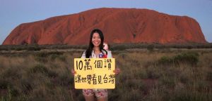 ▲10年前，陳玟臻在澳洲最具代表性的自然地景烏魯魯前面舉牌「十萬個讚，讓世界看見台灣」。（圖／翻攝BaoBao的世界最棒工作臉書）
