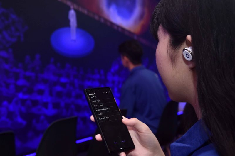 ▲配戴 Auracast 廣播音訊支援的耳機,可直接收聽到從公共場所喇叭中播放出來的音訊。(圖/官方提供)