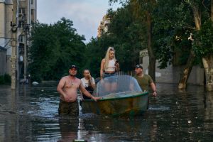 ▲新卡科夫卡水壩遭破壞後湧出大量洪水，烏克蘭民眾涉水撤離。（圖／美聯社／達志影像）