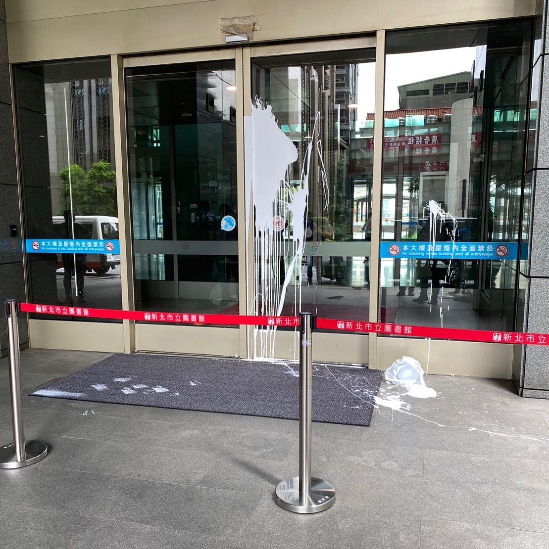 ▲新北市府中山路大門今（16）日上午，遭到一名身份不明男子潑白漆，他獨自一人騎車到新北市府後，下車拿著整桶白漆潑灑，隨後逃逸。（圖／翻攝畫面）