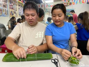 ▲越南新住民紅青和丈夫洪先生體驗包粽子的樂趣。（圖／移民署嘉義市服務站提供）