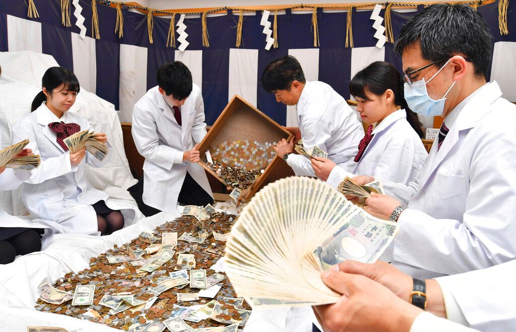 ▲日本神社會收到大量硬幣的「賽錢」（香油錢），但存到銀行會被收取大筆手續費，導致神社陷入困境。圖為神社人員計算新年香油錢。（圖／美聯社／達志影像）