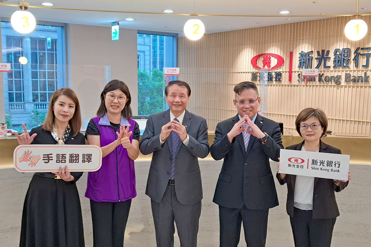 ▲新光銀行董事長賴進淵(中)、總經理李正國(右二)、台灣手語翻譯協會理事長魏如君(左二)、法遵長周秀貞(左一)及郭文香副總(右一)共同用手語分別表達銀行、服務及我愛您，為聽障人士提供金融友善服務。(圖/品牌提供)