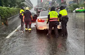 ▲因強降雨造成積水，水深約3/4輪胎深，且有1車輛故障拋錨於匝道口，三民二分局員警獲報後立即協助排除故障車輛。（圖／三民二局提供）