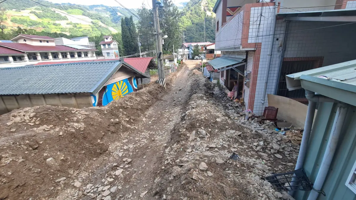 ▲豪雨帶來的土石，一度淹沒都達國小（左）前的村落街道。（圖／南投縣政府提供，2023.08.21）