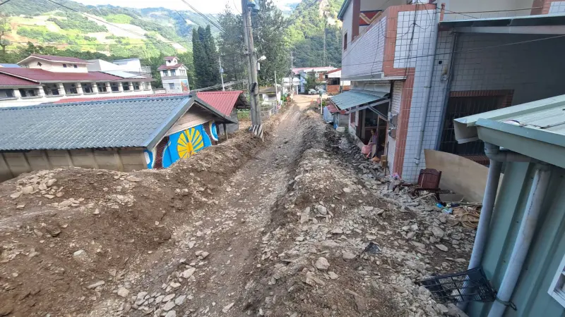 ▲豪雨帶來的土石，一度淹沒都達國小（左）前的村落街道。（圖／南投縣政府提供，2023.08.21）