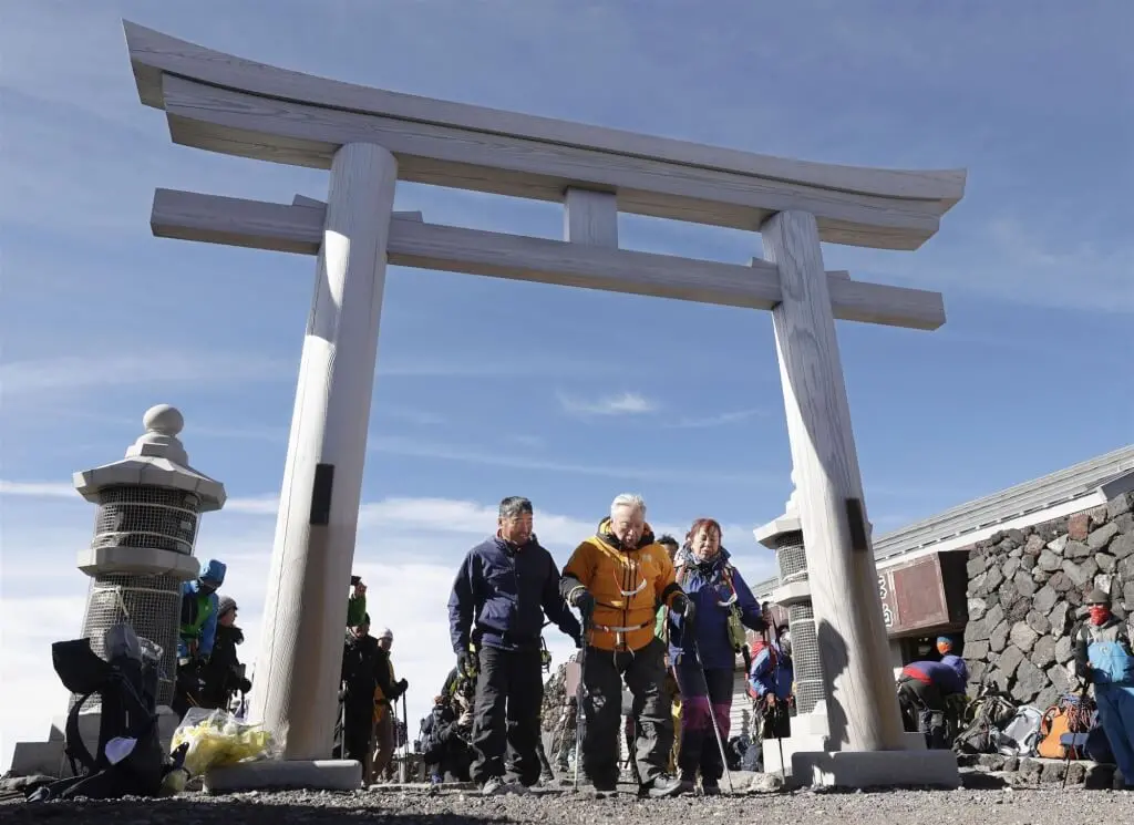 ▲圖為三浦雄一郎（中）穿過富士山頂的鳥居。（共同社）