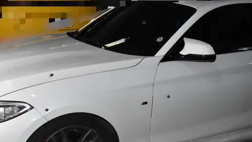 ▲白色BMW座車因槍擊導致擋風玻璃和車身留下彈孔。（圖／記者郭凱杰翻攝）