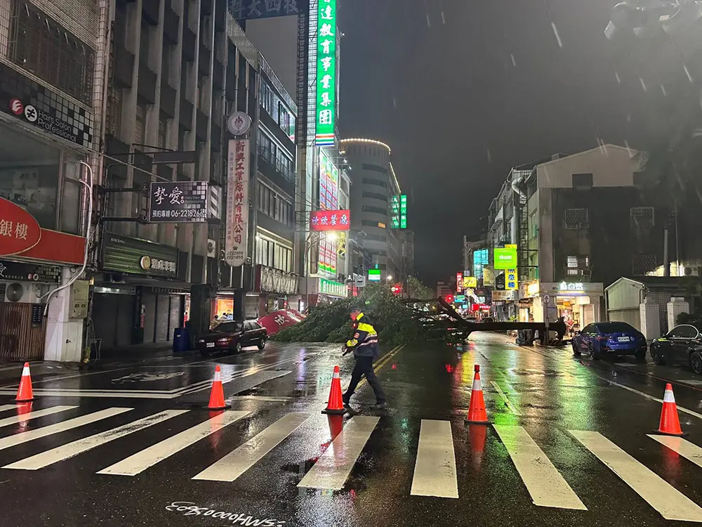▲民族路二段的樹木倒塌橫躺整個路面，警方現場協助交管，工務局迅速處理完成倒塌的樹木恢復交通（圖／台南市工務局提供）