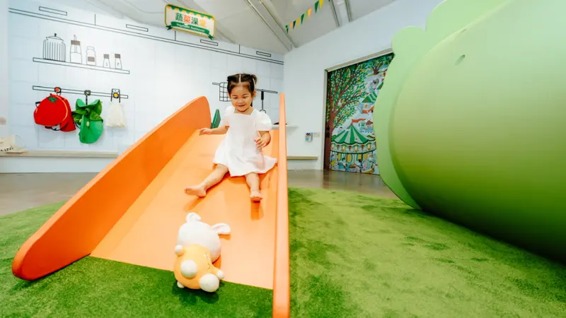 ▲〈蔬菜遊戲場〉由藝術家林玲蓉彩繪最受歡迎的紅蘿蔔溜滑梯，小朋友特別帶著兔兔玩偶一起溜。（圖／內惟藝術中心提供）