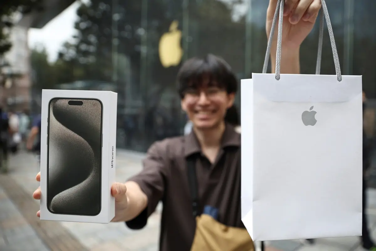 ▲有日媒指出，受到日圓匯率走貶等因素影響，iPhone 15入門款在當地的價格之低，僅次中國。圖為展示購得新機的東京民眾。（圖／美聯社／達志影像）