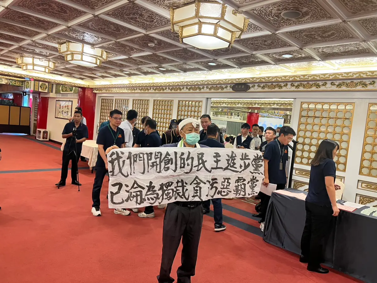 ▲創黨元老、前立委魏耀乾在場外舉布條抗議，秘書長許立明恰巧在後方。（圖／記者陳佩君攝，2023.09.27）