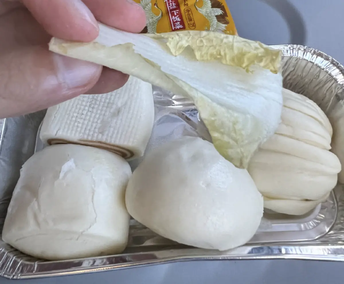 ▲一名大陸網友在搭乘中國南方航空時，機上提供的飛機餐竟是4顆小饅頭、1包榨菜及1片白菜，讓他覺得相當奇特，便拍下來PO上網分享。（圖／翻攝自微博）