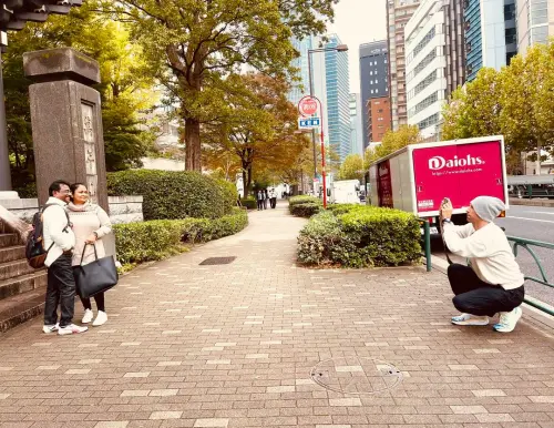 ▲克里斯馬汀（右）充當攝影師，在日本街頭幫民眾拍照。（圖／翻攝自Coldplay臉書）