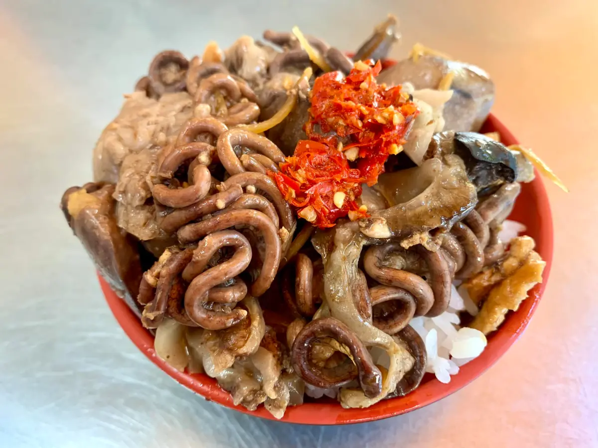 ▲一名網友近日在台北市三重區吃到一碗特別的小吃，只見上頭鋪滿油亮的蜷曲物，讓人直覺聯想到正在蠕動的蚯蚓，但其實這是南部暗黑料理「虱目魚腸」。（圖／翻攝自爆廢1公社）